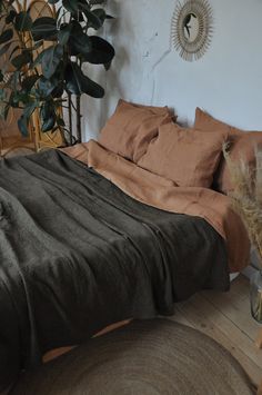 a bed with brown sheets and pillows in a room next to a potted plant