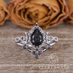 a black and white diamond ring sitting on top of a wooden table next to roses