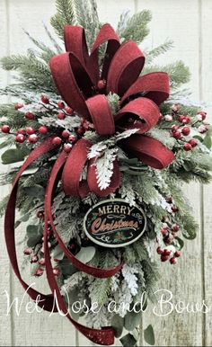 a christmas wreath hanging on the side of a wooden wall with red ribbon and bow