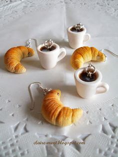 four croissants and two cups of coffee on a white tablecloth with doily