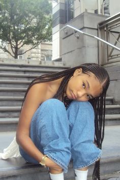 a woman sitting on the steps with her hands behind her head and looking at the camera