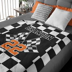 a bed with an orange and black blanket on it