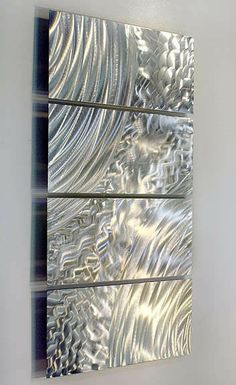 three metal panels mounted to the side of a wall in front of a white wall