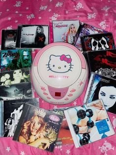 there are many cd's and cds on the pink bed sheet with hello kitty