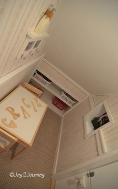 an overhead view of a small room with a desk and shelves on the wall next to it