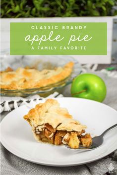 a slice of apple pie on a white plate with a green apple in the background