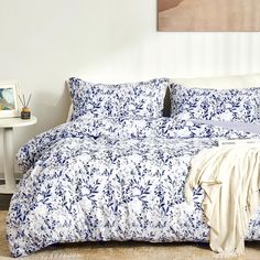 a bed with blue and white comforter in a room next to a painting on the wall