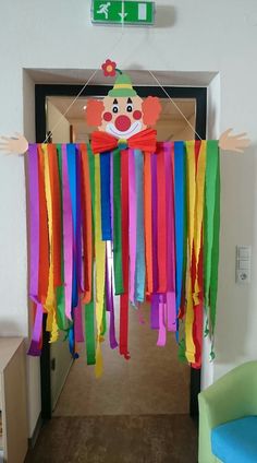 a hallway decorated with colorful streamers and a clown head hanging from the ceiling above it