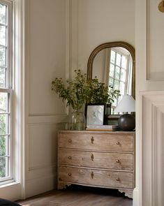 a dresser with a mirror and flowers on it