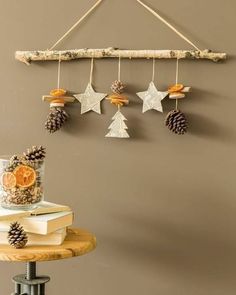 pine cones, oranges and other decorations are hanging from a branch on the wall