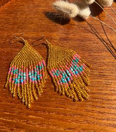 a pair of beaded earrings sitting on top of a wooden table