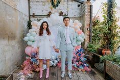 a man and woman standing next to each other in front of balloons