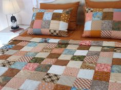 a bed covered in lots of different colored patchwork quilts and pillow shampoos