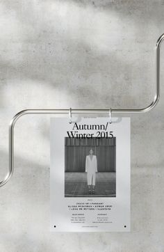 a poster hanging on a metal bar in front of a concrete wall with the words autumn / winter 2013