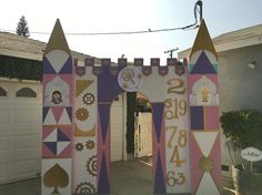 a colorful gate with numbers on it in front of a house that is painted pink, purple and gold