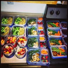 many plastic containers filled with different types of vegetables and fruits in them, all on top of each other