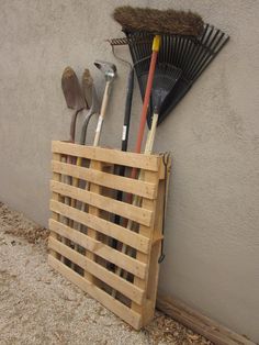 a wooden crate filled with gardening tools next to a wall