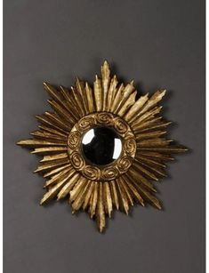 an ornate gold sunburst with a black stone in the center on a gray background