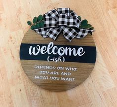 a wooden sign that says welcome with a bow on the front and back of it