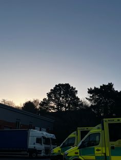 ambulances are parked in the parking lot at dusk