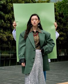 a woman holding up a green sign in front of her