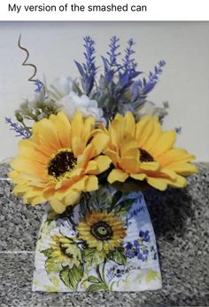 a vase filled with yellow sunflowers on top of a granite counter next to a wall