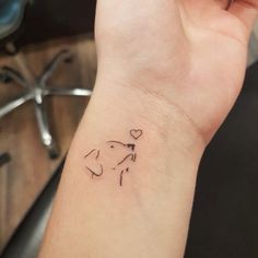 a small tattoo on the wrist of a woman's arm with a dog and heart