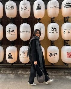 a woman walking down the street in front of lanterns