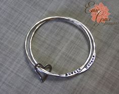 This beautiful mother or grandmother bangle bracelet set is made of sterling silver (92.5%) or fine silver (99.9%) and hand stamped with the names of your loved ones or the message of your choice. Includes 2 sturdy bangles (contact me for more bangles), each stamped with up to 4 names each. So we can fit 8 names total on the 2 bracelets. Photo sample shows 1 name on each, but I can add up to 4 per bangle. Names are only stamped on one side. It is held together with a hand crafted sterling sil... Personalized Sterling Silver Bangle For Anniversary, Engraved Sterling Silver Bangle Name Bracelet, Personalized Silver Bangle For Anniversary, Personalized Silver Bangle, Engraved Sterling Silver Name Bangle, Sterling Silver Stamped Bangle For Gift, Sterling Silver Stamped Bangle As Gift, Personalized Silver Bangle For Mother's Day, Personalized Sterling Silver Name Bracelet Bangle