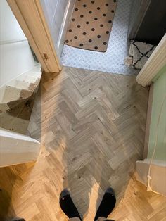 a person standing on the floor in front of a bathroom door looking down at their feet