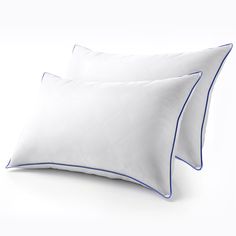 two white pillows with blue piping on them