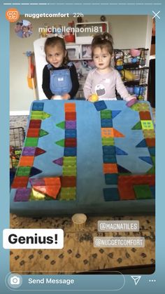 two young children standing in front of a giant quilt