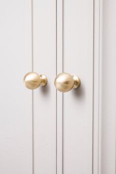 two gold knobs on a white door