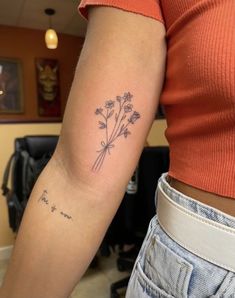 a woman with a tattoo on her arm holding a flower in one hand and the other