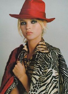 a woman wearing a red hat and coat with her hands on her chest, posing for the camera