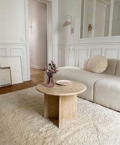 a living room with a couch, table and mirror on the wall in it's corner