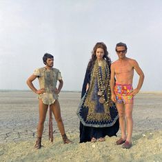 two men and a woman standing on the beach