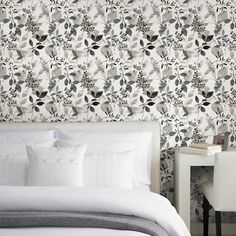 a bed with white sheets and pillows in front of a wallpapered headboard