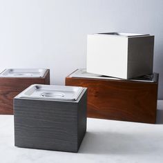 three wooden boxes sitting on top of each other in front of a white wall and floor