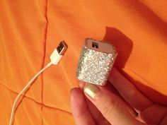 a hand holding an electronic device that is plugged into a charger and has glitter on it