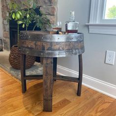 an old barrel turned into a side table with a bottle on it and a plant in the corner