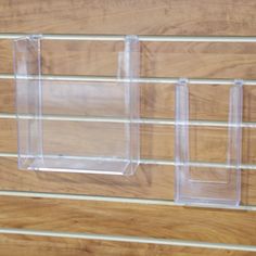 three clear acrylic boxes sitting on top of a wooden table next to a wall