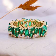 an emerald colored bracelet with crystal stones and leaves on the table in front of it