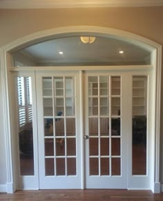 an arched doorway leading to a living room with french doors and glass panels on the front door