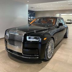 a black rolls royce parked in a showroom