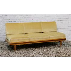 a yellow couch sitting on top of a carpet covered floor next to a white brick wall