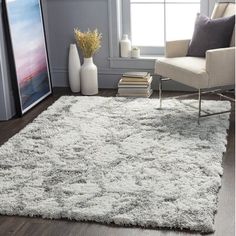 a white rug in a living room next to a chair and vase with flowers on it