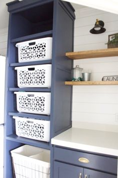 the shelves in this kitchen are painted blue and have white baskets on them, along with other items