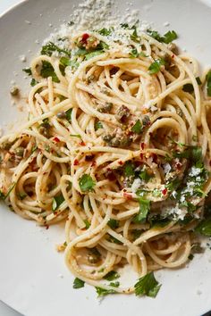 a white plate topped with pasta and sauce covered in parmesan sprinkles