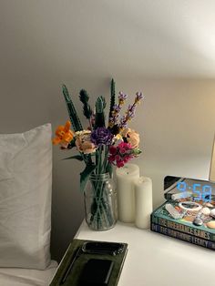 a vase with flowers and candles sitting on a table next to a book, candle holder and tray